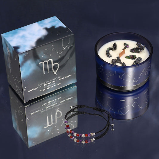 Candle with decorative elements and a box featuring astrological symbols on a dark background