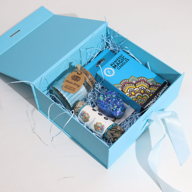 Blue gift box filled with a candle, crystal and botanical self-care gifts
