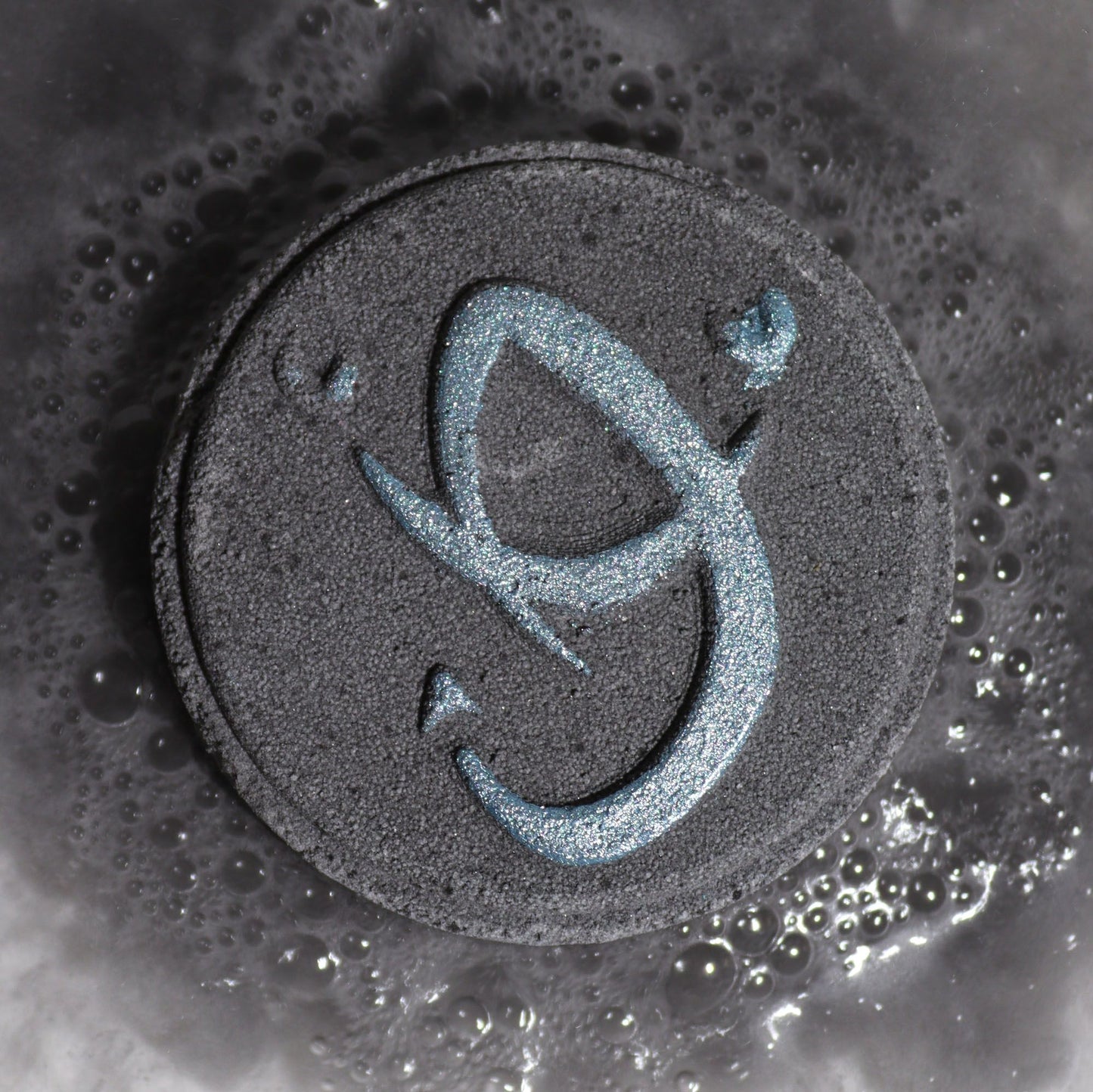 Black circular object with a blue symbol on a textured surface