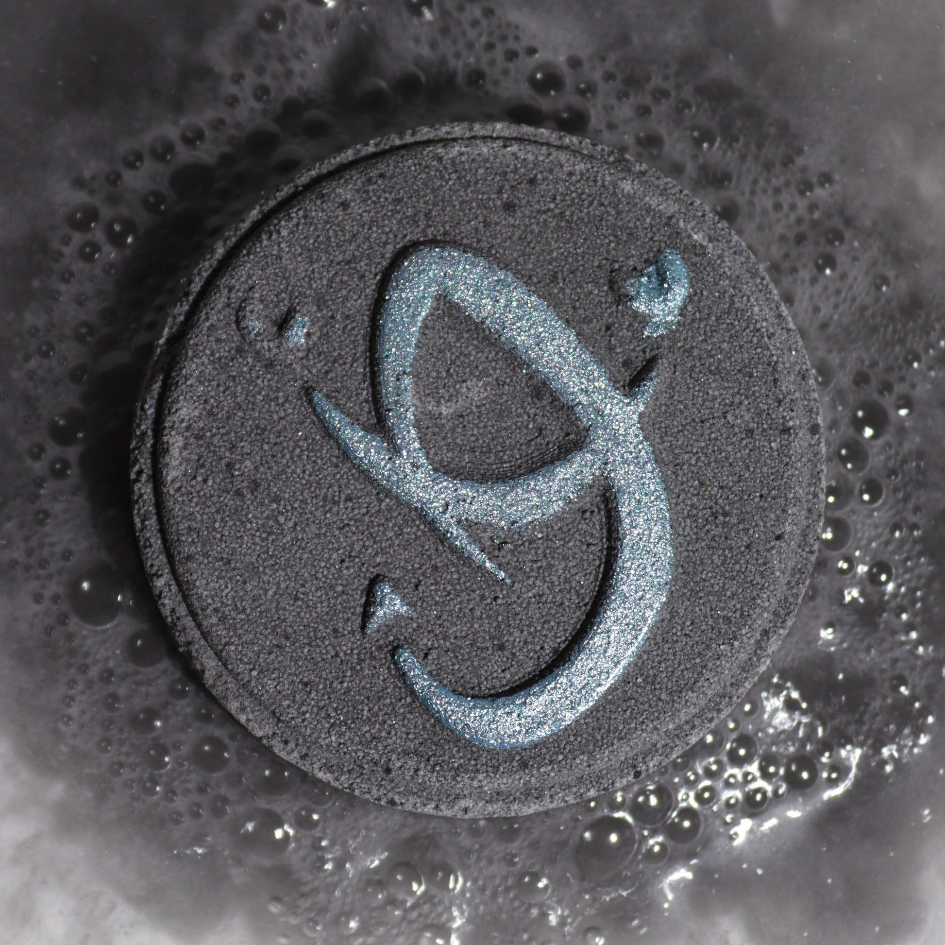 Black circular object with a blue symbol on a textured surface